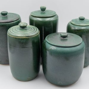 The image is of 5 tall stoneware lidded jars in a jade green glaze